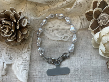 Fresh water peal phone wristlet on a textured neutral background