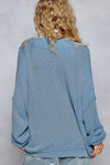 A woman facing backwards wearing the Lakehouse Cardigan and blue pants.
