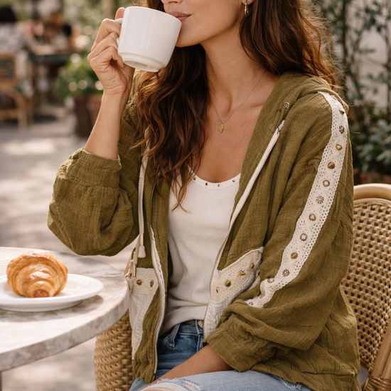 woman sitting at an outdoor café wearing an olive boho jacket with crochet detail styled with jeans and a tank, lightweight boutique jacket for casual everyday outfits and effortless layering