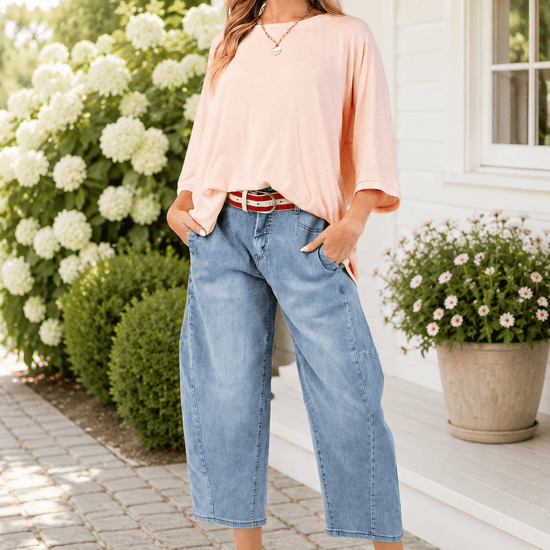 A model wearing a straw hat, light wash denim, and the Peach Oversized Dolman Sleeve Top and flats