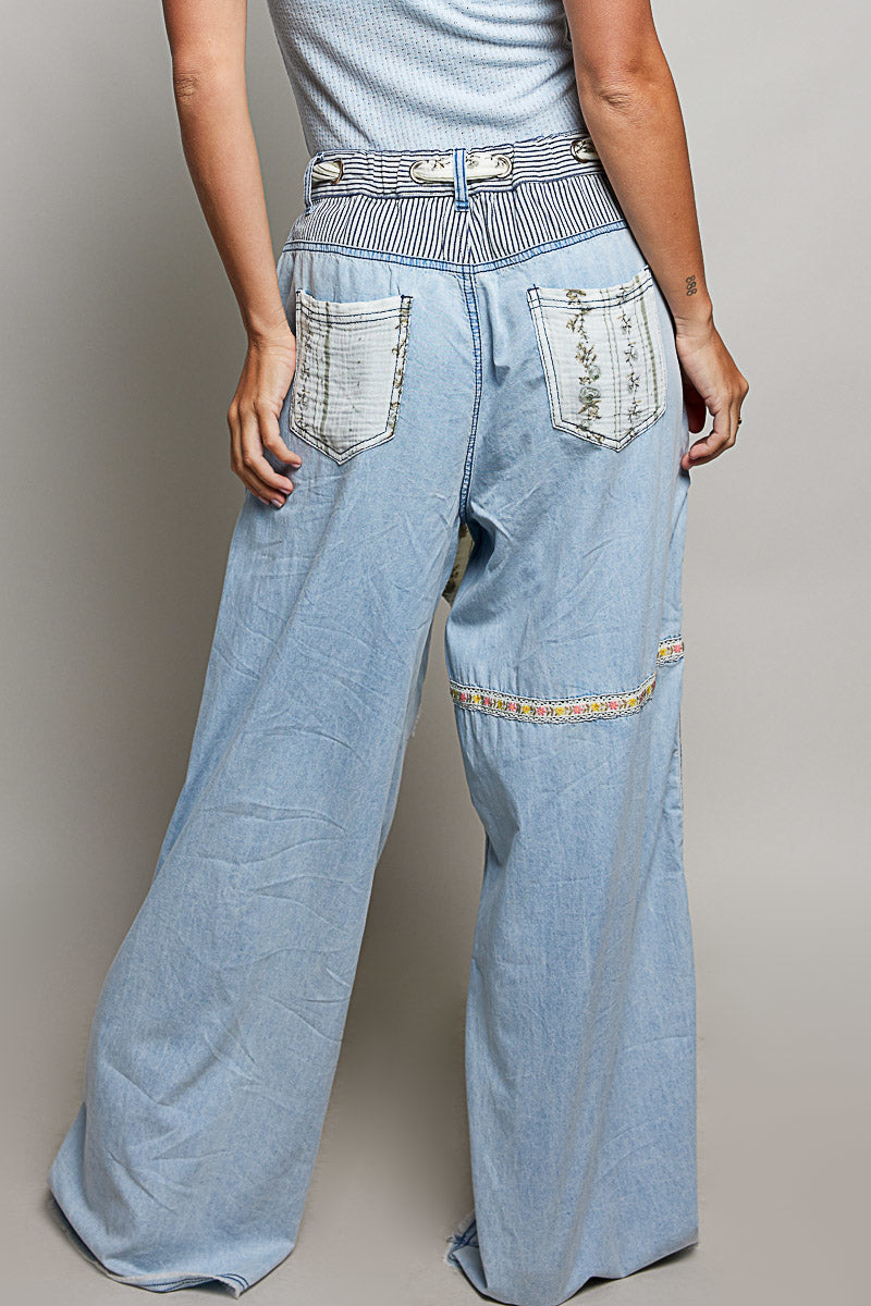 Back view of woman wearing Pol clothing wide leg patchwork jeans with a grey background.