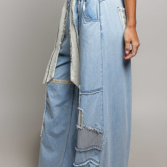 Sideview of a woman wearing Pol Clothing Wide Leg Patchwork Jeans with a grey background.