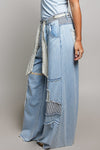 Sideview of a woman wearing Pol Clothing Wide Leg Patchwork Jeans with a grey background.