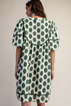 Back view of a woman wearing polka dot linen mini dress with a cream background.