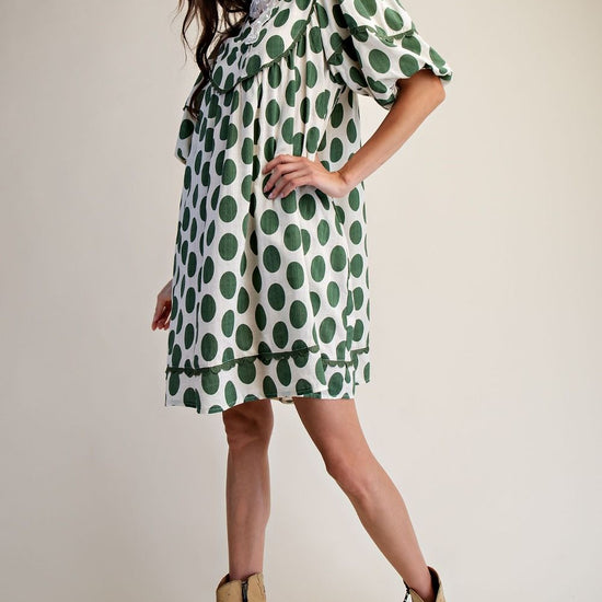 Side view of woman wearing polka dot linen mini dress with a cream background