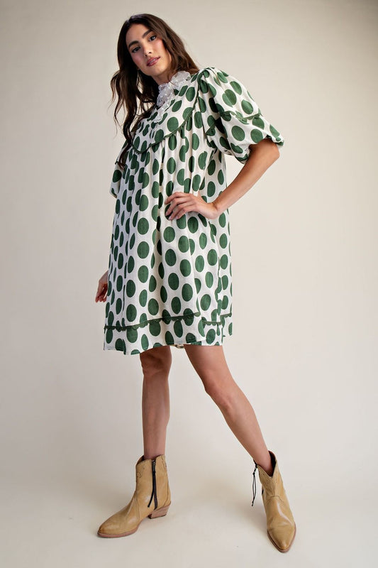 Side view of woman wearing polka dot linen mini dress with a cream background