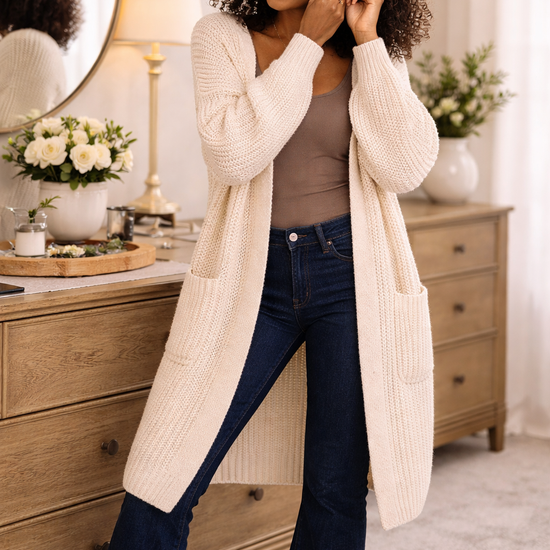 woman wearing a long-oversized cream cardigan with dark bootcut jeans in a cozy getting ready setting, soft knit cardigan for women, casual fall outfit layering piece, boutique boho style cardigan
