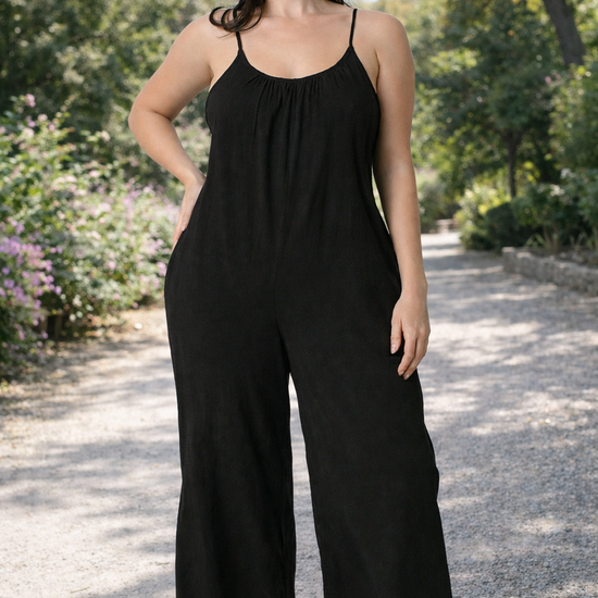 Women's black wide-leg cropped jumpsuit with spaghetti straps styled casually with sandals outdoors