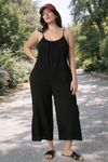 Women's black wide-leg cropped jumpsuit with spaghetti straps styled casually with sandals outdoors