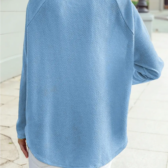 Back view of a soft blue textured jacquard shift top with relaxed fit and long sleeves styled with white jeans for an everyday casual look