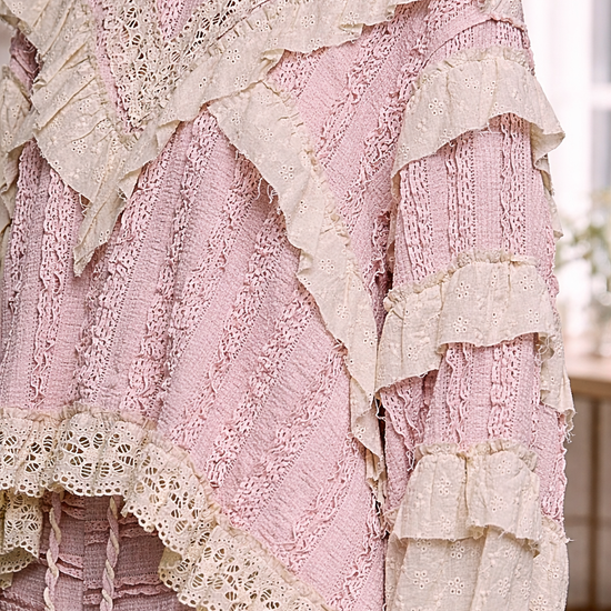 Close-up of blush pink boho lace ruffle top with cream eyelet detailing and layered textures, styled in a soft neutral interior setting