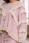 Close-up of blush pink boho lace ruffle top with cream eyelet detailing and layered textures, styled in a soft neutral interior setting