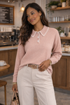 Blush pink sweetheart collar knit sweater on a woman styled with neutral trousers and accessories in a modern coffee shop setting.