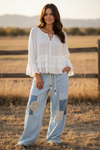 Woman wearing the Aria Crinkle Ruffle Top with Sky Breeze Patchwork Boho Wide Leg Pants, standing in a field.