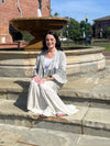 Woman sitting on stone steps wearing the Boho patchwork lace ruffle shrug and Grey boho tiered patchwork pants.