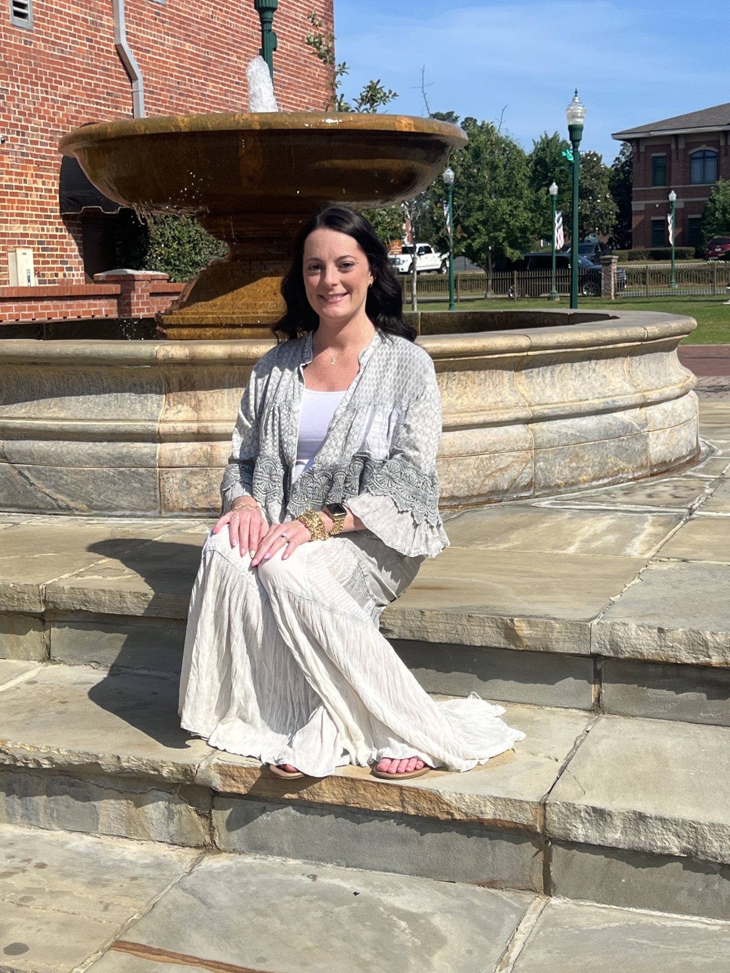 Woman sitting on stone steps wearing the Boho patchwork lace ruffle shrug and Grey boho tiered patchwork pants.