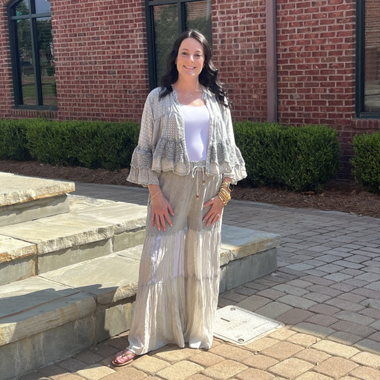 Woman wearing the Boho Ruffle Lace Shrug and Grey Boho Tiered Patchwork pants in an outdoor setting.