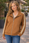 Middle aged woman wearing a caramel zip up track jacket with cream stripe sleeces styled with jeans and a leopard blouse in a casual outdoor lifestyle setting