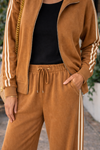 Detail view of caramel wide leg lounge pants featuring drawstring waistband and cream stripe track detail styled with matching athleisure jacket