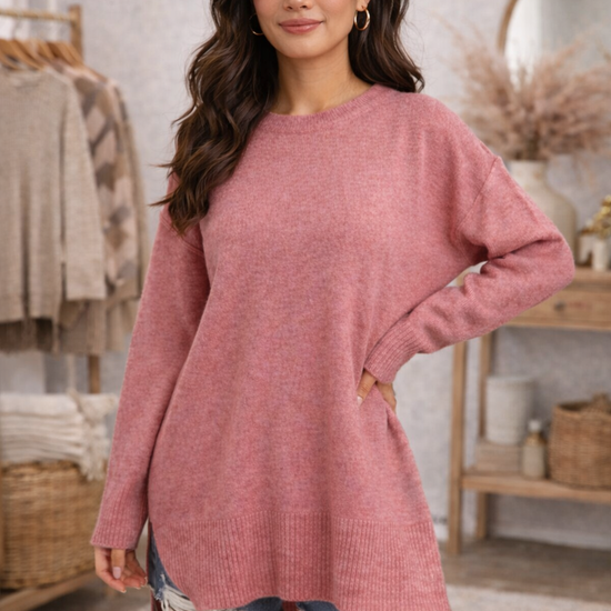 Woman wearing a dusty rose cozy oversized sweater and denim shorts in a  boutique setting.
