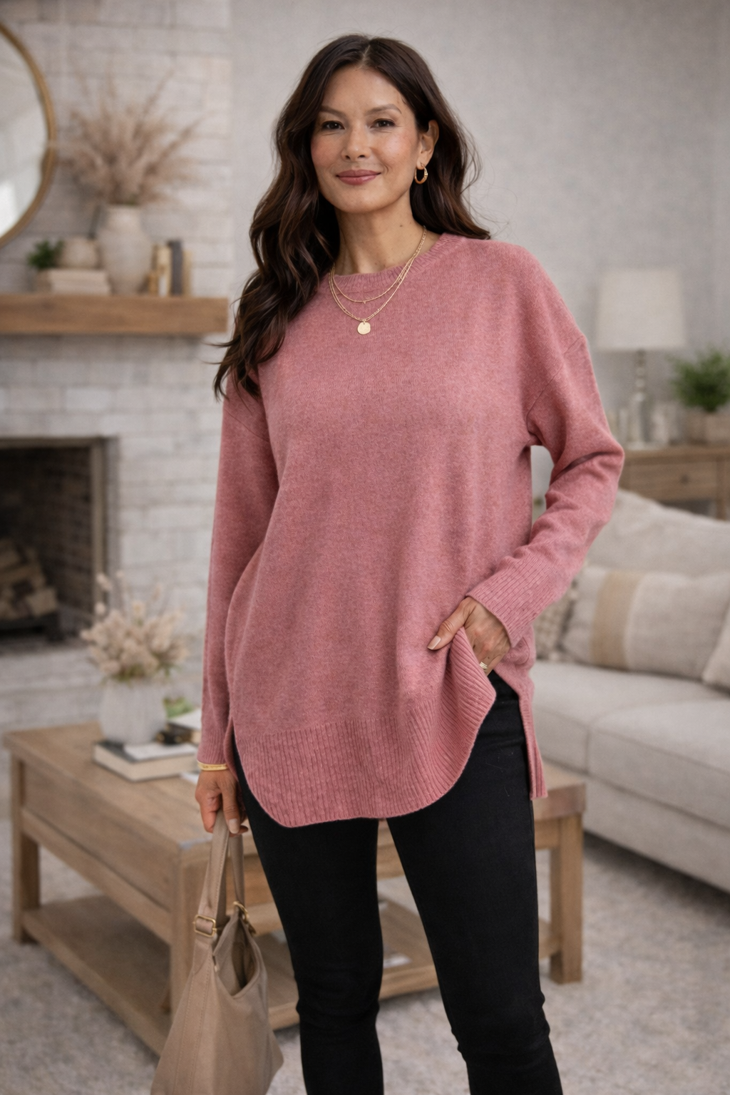 A woman wearing a dusty rose oversized sweater in a cozy living room.