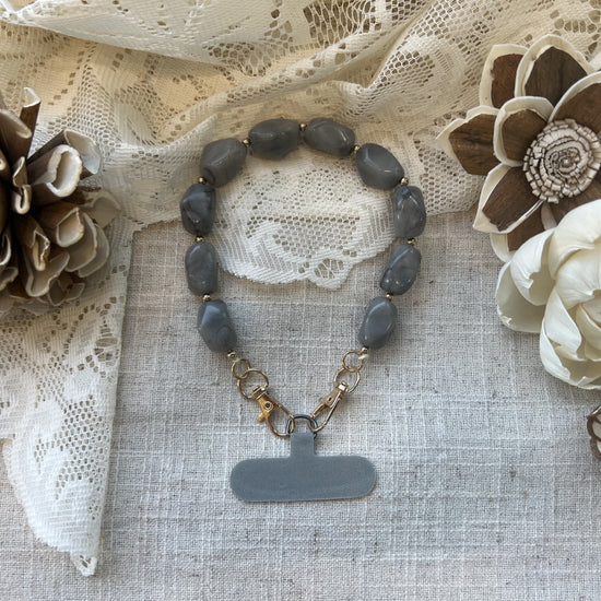 Grey marble phone wristlet on a textured neutral background