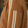 Close-up detail of caramel stripe fabric texture on the track jacket