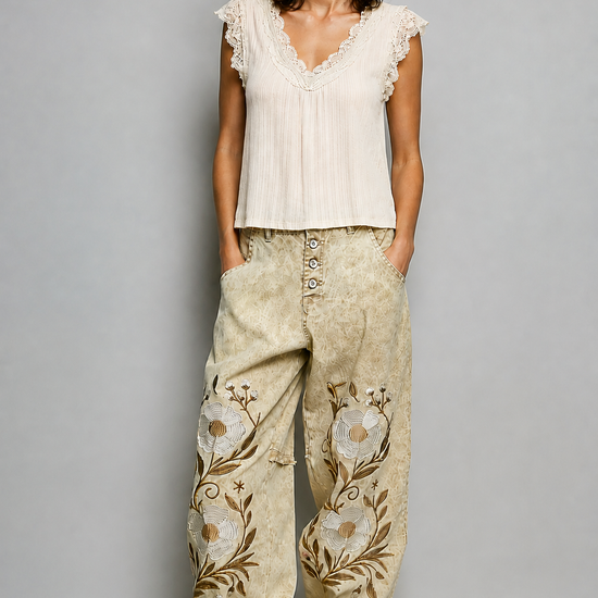 Model wearing embroidered floral jogger pants in natural sand with vintage wash and metal button fly
