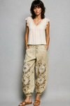 Model wearing embroidered floral jogger pants in natural sand with vintage wash and metal button fly