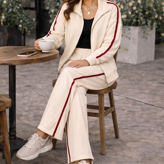 Close-up detail of women’s ivory wide leg athleisure track pants with crimson stripe, elastic waistband, and pocket styling in casual lifestyle outfit