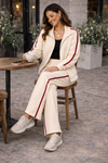 Close-up detail of women’s ivory wide leg athleisure track pants with crimson stripe, elastic waistband, and pocket styling in casual lifestyle outfit