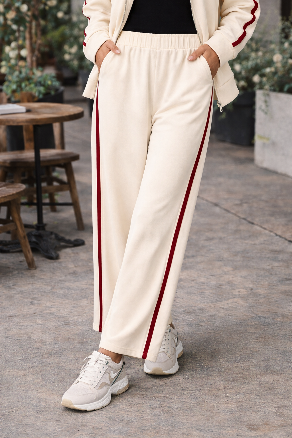 Women's ivory wide leg athleisure pants with crimson side stripe styled with sneakers in casual everyday outfit at outdoor café