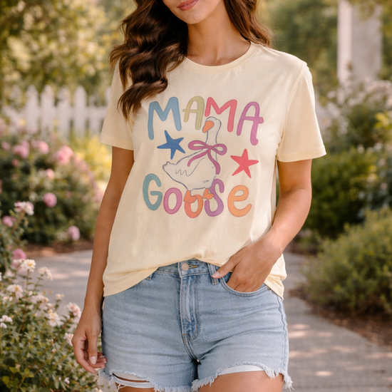woman wearing mama goose pastel graphic tee with denim shorts walking outdoors in a sunny garden setting