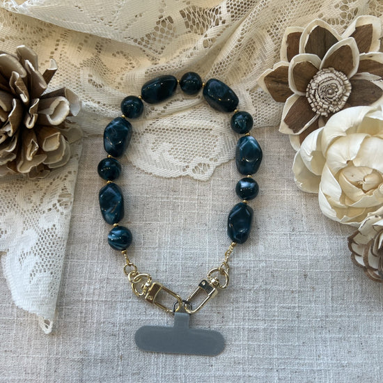Midnight teal phone wristlet on a textured neutral background