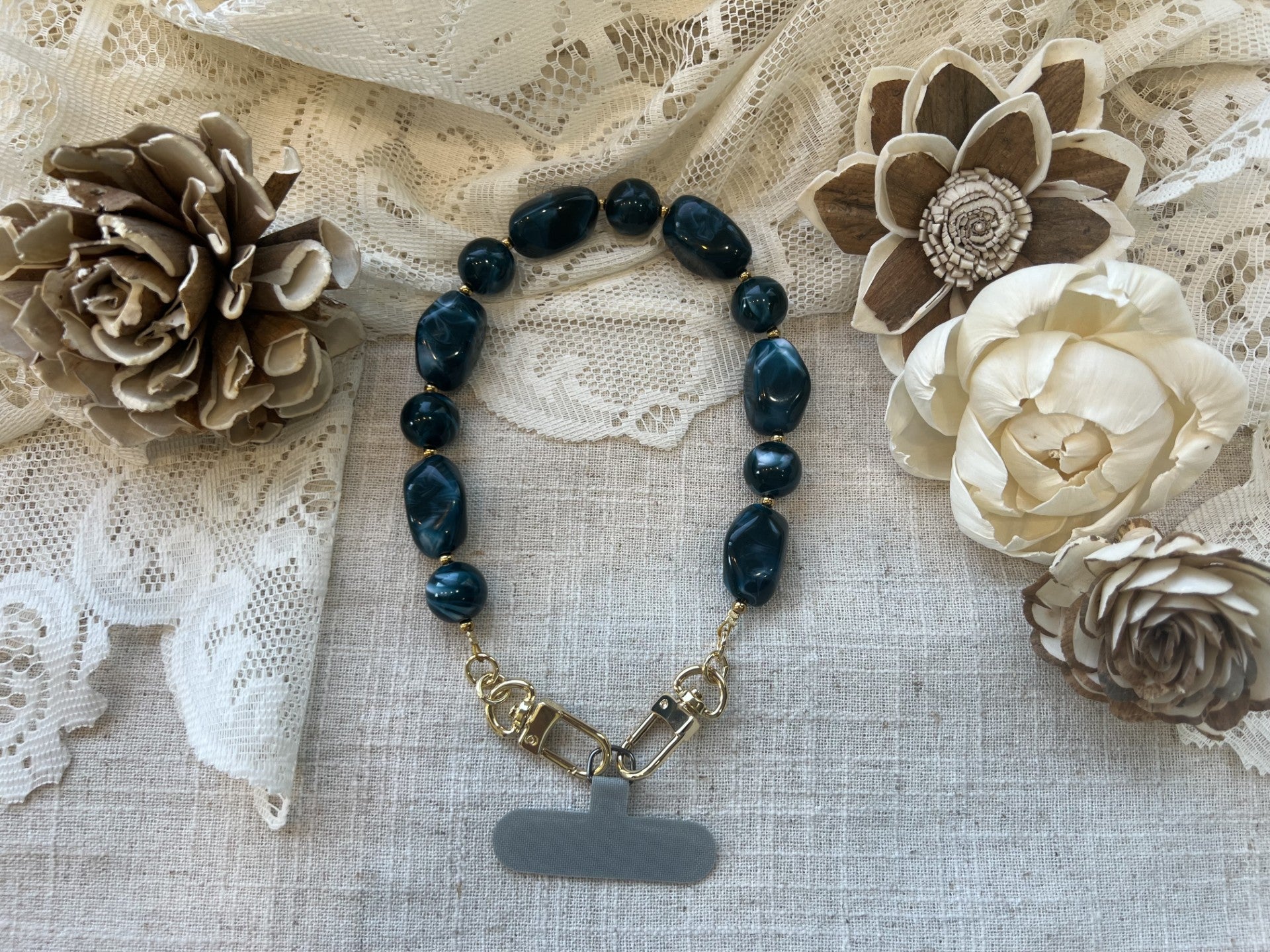 Midnight teal phone wristlet on a textured neutral background