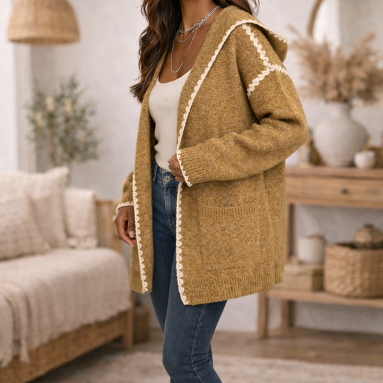 Woman wearing a mustard hooded boho cardigan, jeans in a cozy living room