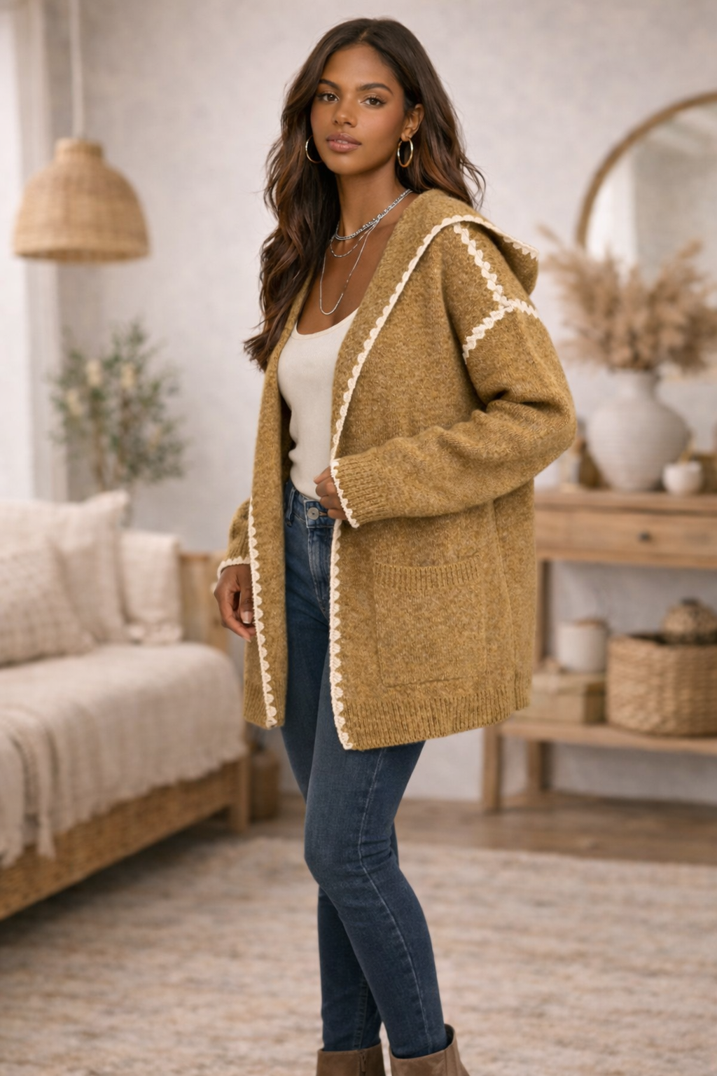 Woman wearing a mustard hooded boho cardigan, jeans in a cozy living room