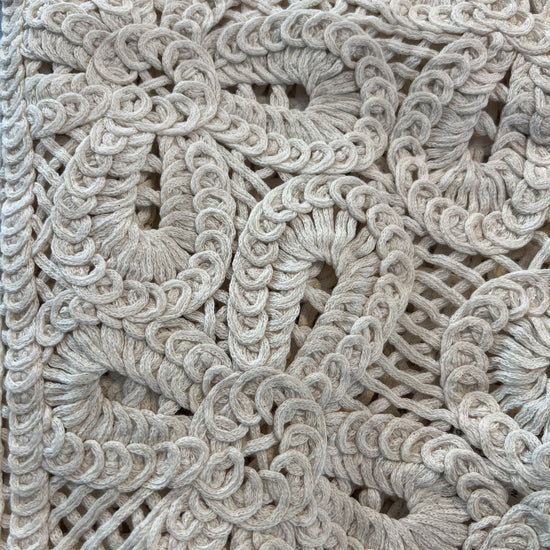 Close-up detail of natural crochet button vest showcasing intricate open-knit floral pattern and textured stitching in a soft neutral tone