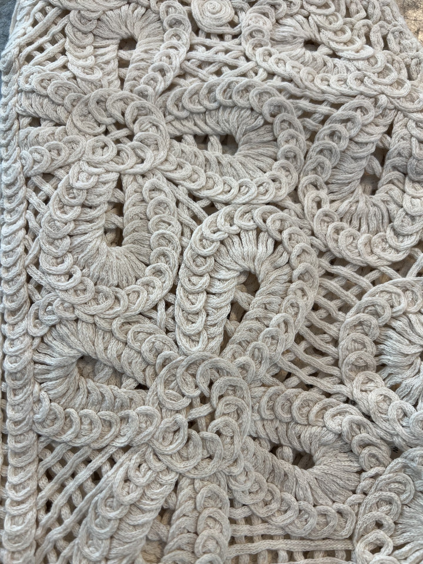 Close-up detail of natural crochet button vest showcasing intricate open-knit floral pattern and textured stitching in a soft neutral tone