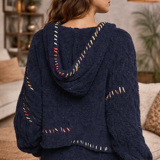 Navy boho textured cozy zip jacket with artisan stitching and hood shown from back on brunette model in warm neutral boutique interior.