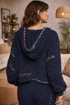 Navy boho textured cozy zip jacket with artisan stitching and hood shown from back on brunette model in warm neutral boutique interior.