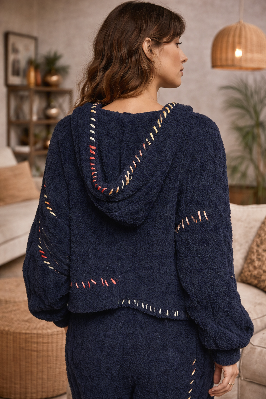 Navy boho textured cozy zip jacket with artisan stitching and hood shown from back on brunette model in warm neutral boutique interior.