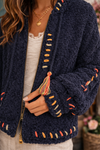 Close up of navy boho textured cozy zip jacket showing soft sherpa texture, colorful stitching and tassel detail.