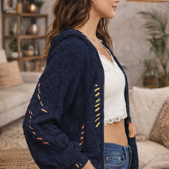 Navy boho textured cozy zip jacket with artisan stitching shown in side profile on brunette model in a warm boho boutique interior.