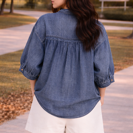 back view of woman wearing relaxed chambray button down top worn untucked with high waisted tailored shorts outdoors