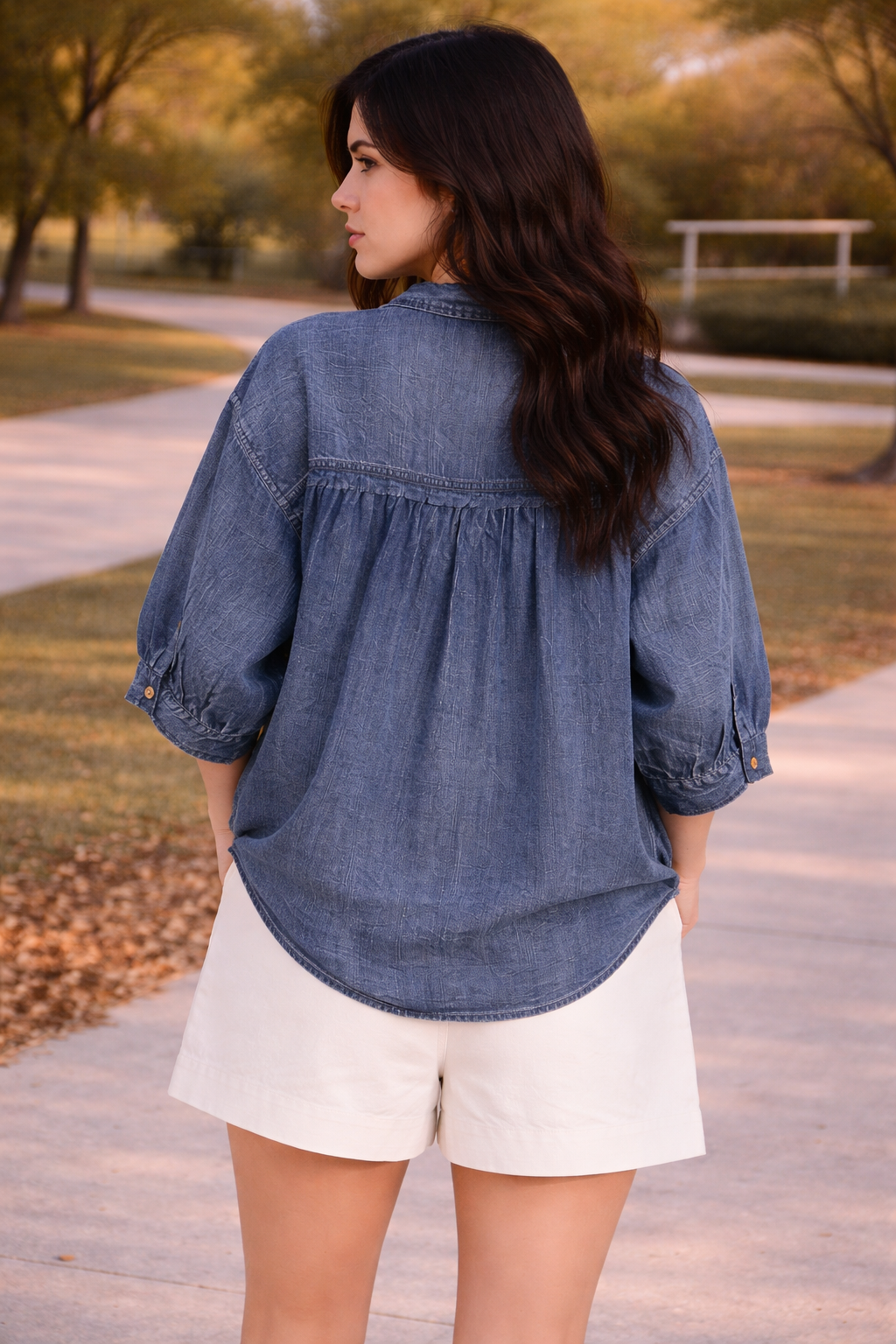 back view of woman wearing relaxed chambray button down top worn untucked with high waisted tailored shorts outdoors