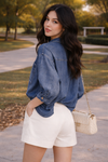 side view of woman wearing relaxed chambray button down top with high waisted tailored shorts and woven handbag outdoors