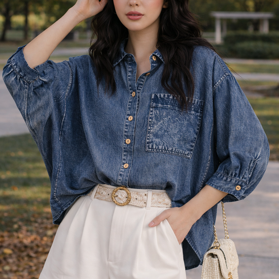 woman wearing relaxed chambray button down top with high waisted tailored shorts and woven handbag outdoors