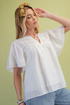 side view of a model wearing the Ivory Lace Pintuck Flutter Sleeve Blouse with a green background