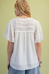 A model is standing in front of a green background showing the back view of the Ivory Lace Pintuck Flutter Sleeve Blouse